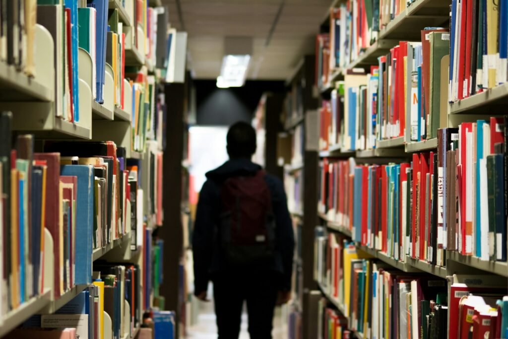 man with backpack beside books
